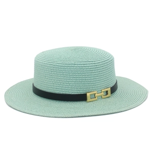 Dettaglio di cappello in paglia verde menta con trama intrecciata e cinturino nero con fibbia oro