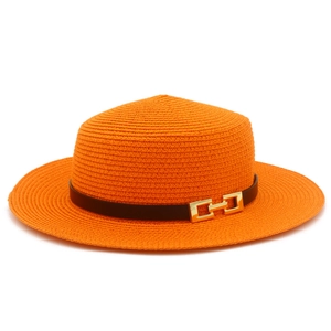 Dettaglio cappello di paglia arancione con fascia in pelle nera e fibbia dorata