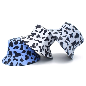 Detail of cow print bucket hats in black, white and blue patterns on plain background