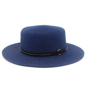 Detail of navy blue straw boater hat featuring gold stud band and metal ring accent