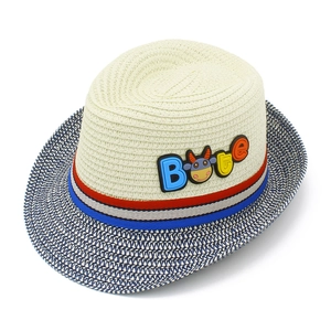 Dettaglio del cappello di paglia per bambini con nastro tricolore e ornamento di mucca