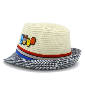 Dettaglio cappello di paglia per bambini con nastro a righe e simpatica toppa di mucca