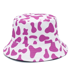 Detail of cotton sun bucket hat featuring a trendy purple cow print pattern on white base