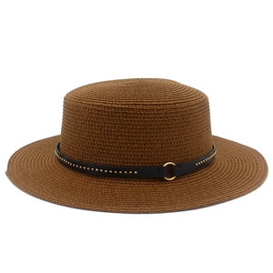 Detail of caramel straw hat featuring a black leather band with gold studs and a metal ring