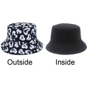 Detail of reversible bucket hat with white heart patterns and plain black inner side