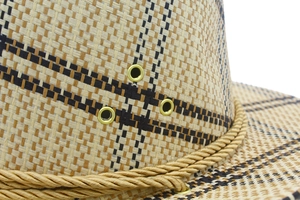 Detailed macro view of woven straw cowboy hat texture with golden metal ventilation eyelets