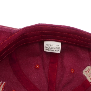 Detail view of the internal 100% cotton wash label on a burgundy vintage baseball cap