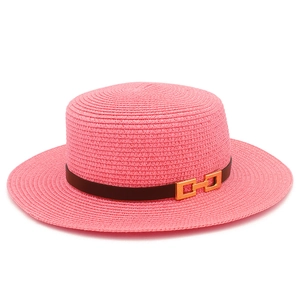 Dettaglio cappello di paglia rosa con nastro nero e fibbia geometrica dorata