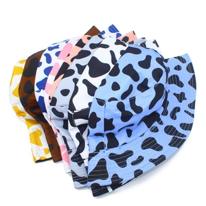 Stack of multi-colored cow print bucket hats showing stitching detail and vibrant fabric