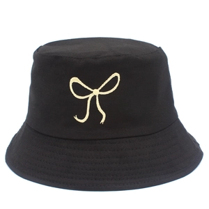 Detailed view of beige bow embroidery on a black cotton canvas bucket hat surface