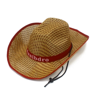 Détail d'un chapeau de cowboy en paille avec bordure rouge et mentonnière noire