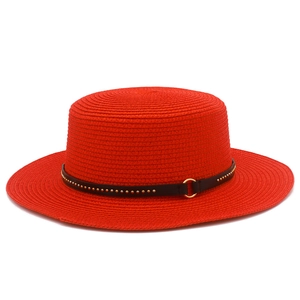 Detailed macro view of red straw hat with black leather belt and gold rivet accents