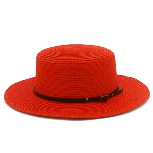Detailed macro view of bright red straw boater hat with black studded leather belt