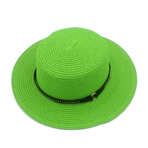 Macro view of neon green straw hat featuring black leather band and gold metal studs