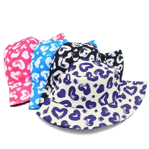 Detail view of heart print bucket hats in four colors: pink, blue, black, and beige