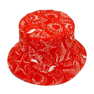 Top view of red bucket hat with white starfish and seashell patterns on twill fabric