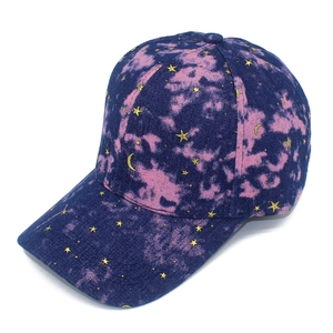 Detail of embroidered gold stars and moons on navy pink tie-dye nebula baseball cap