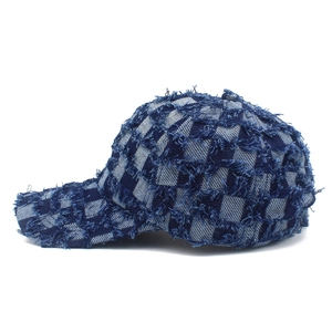 Detail of checkered denim baseball cap showing distressed fringe and frayed texture details