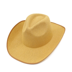 Close-up of warm yellow woven cowboy hat with brown trim and hollow weave texture