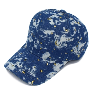 Close-up of tie-dye denim baseball cap with gold star and moon patterns