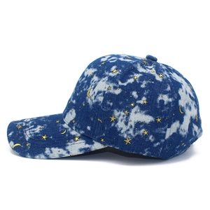 Detail view of tie-dye baseball cap featuring metallic gold star and moon patterns
