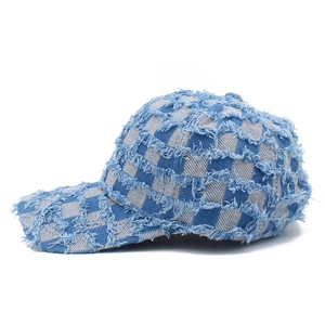 Close-up of blue and white checkerboard denim baseball cap with distressed frayed edge detail