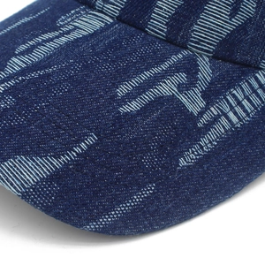Macro detail of distressed denim baseball cap showing blue jacquard texture and stitching