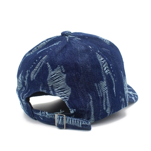 Close-up of distressed denim baseball cap with adjustable metal buckle and frayed edges
