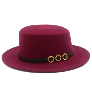 Close-up of wine red flat top felt hat with black belt and three golden diamond ornaments