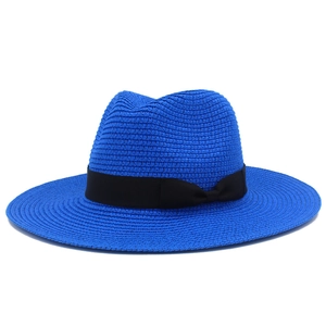 Close-up of bright blue straw beach hat with black ribbon and bow detail on white background