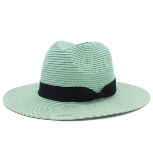 Detail of mint green straw sun hat featuring a fine weave and black ribbon bow