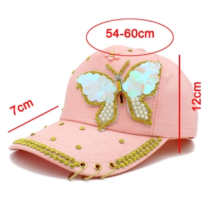Detailed view of pink baseball cap with sequined butterfly and metal ring accents