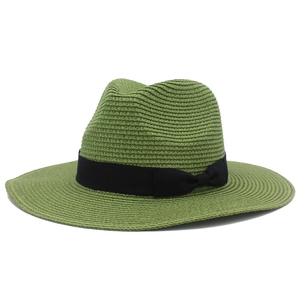 Detail of woven straw texture and black ribbon bow on a green panama sun hat