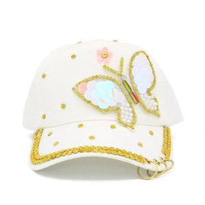 Detail of white baseball cap with butterfly sequin patch and rhinestone brim