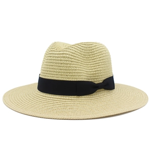 Detail of classic woven straw hat with black ribbon and bow on plain white background