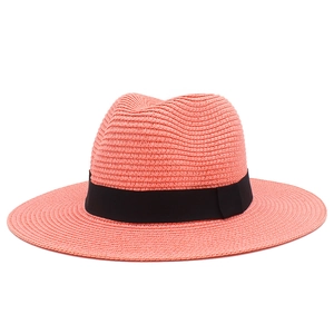 Detail of coral pink straw sun hat showing high-quality woven texture and black ribbon