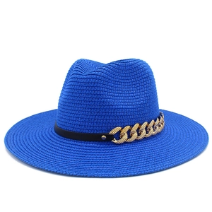 Détail du chapeau de paille bleu avec bande en cuir noir et décoration de chaîne dorée