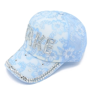 Dettaglio del berretto azzurro con pizzo floreale e scritta FAKE in strass scintillanti