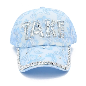 Dettaglio del berretto azzurro con lettere TAKE in strass e raffinati ricami floreali