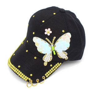 Detail of a black baseball cap with yellow rhinestones, butterfly sequins and metal rings