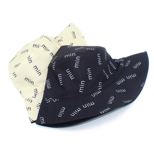 Close-up detail of 'min' letter print on cotton bucket hats in beige and navy blue colors