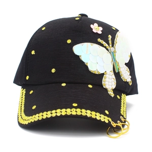 Detail of black baseball cap with sequined butterfly, pink flower, and yellow rhinestones