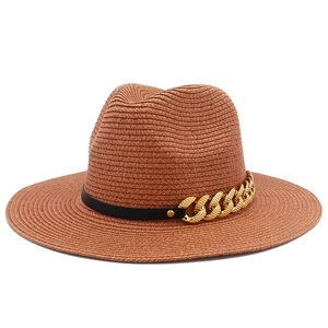 Détail d'un chapeau fedora en paille marron avec ruban cuir noir et chaîne dorée