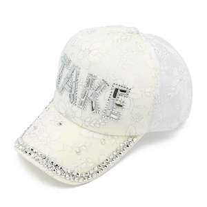 Dettaglio del cappellino in pizzo bianco con lettere TAKE e visiera in strass