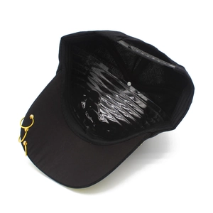 Detail view of black baseball cap featuring three gold metal rings on the brim and adjustable strap