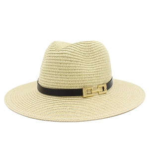 Dettaglio del cappello di paglia beige con fascia nera e fibbia in metallo dorato