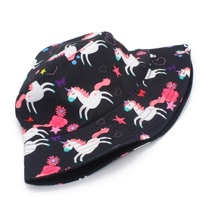 Close-up of black bucket hat with cartoon unicorn, rose, and star prints in soft lighting