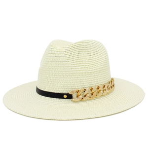 Détail d'un chapeau de paille beige avec bande en cuir noir et chaîne gourmette dorée texturée