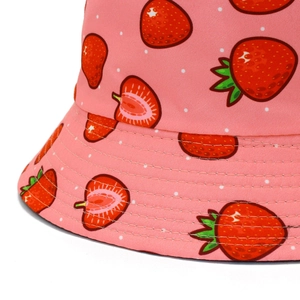 Gros plan du tissu imprimé fraises et des coutures renforcées sur le bob en coton rose