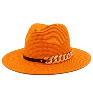 Détail chapeau de soleil orange avec ruban en cuir noir et grosse chaîne dorée